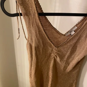 Glittrig guldblus från MNG - Säljer en superfin glittrig guldblus från MNG. Den har en v-ringad design och är ärmlös, perfekt för festliga tillfällen. Blusen är i mycket bra skick och har en elegant passform som framhäver figuren. Perfekt för nyår eller andra speciella tillfällen! ✨