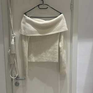 Vit ribbad offshoulder tröja - Säljer en superfin vit ribbad offshoulder tröja. Den är perfekt för både höst och vår med sin mysiga och stilrena design. Tröjan har långa ärmar och en croppad passform som ger en modern look. Perfekt för att klä upp eller ner beroende på tillfälle!