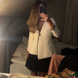 Vit och svart kofta med guldknapp - Snygg vitt och svart kofta med en elegant knapp framtill. Den har en v-ringad design och långa ärmar, perfekt för både fest och vardag. ❣️❣️ 