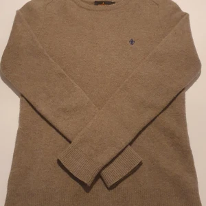 Beige stickad tröja från Morris - Säljer en snygg och stilren beige stickad tröja från Morris. Den har en liten broderad logga på bröstet och långa ärmar med ribbade muddar. Perfekt för höst och vinter, både varm och bekväm. Passar till både vardag och lite finare tillfällen. Priset kan diskuteras.