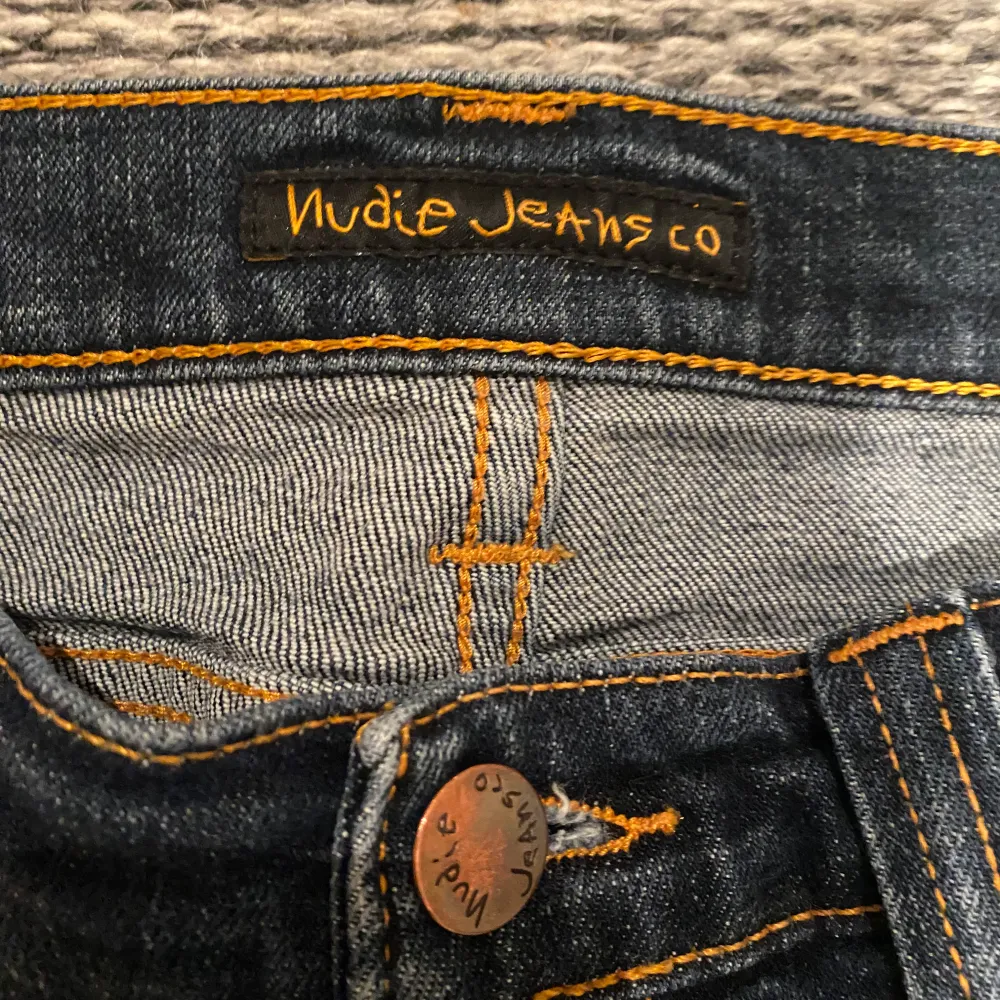 Säljer ett par snygga mörkblå jeans från Nudie Jeans Co i storlek W29 L32. De har en klassisk femficksdesign och orange sömmar som ger en cool kontrast. Perfekta för både vardag och fest! 🕺. Jeans & Byxor.