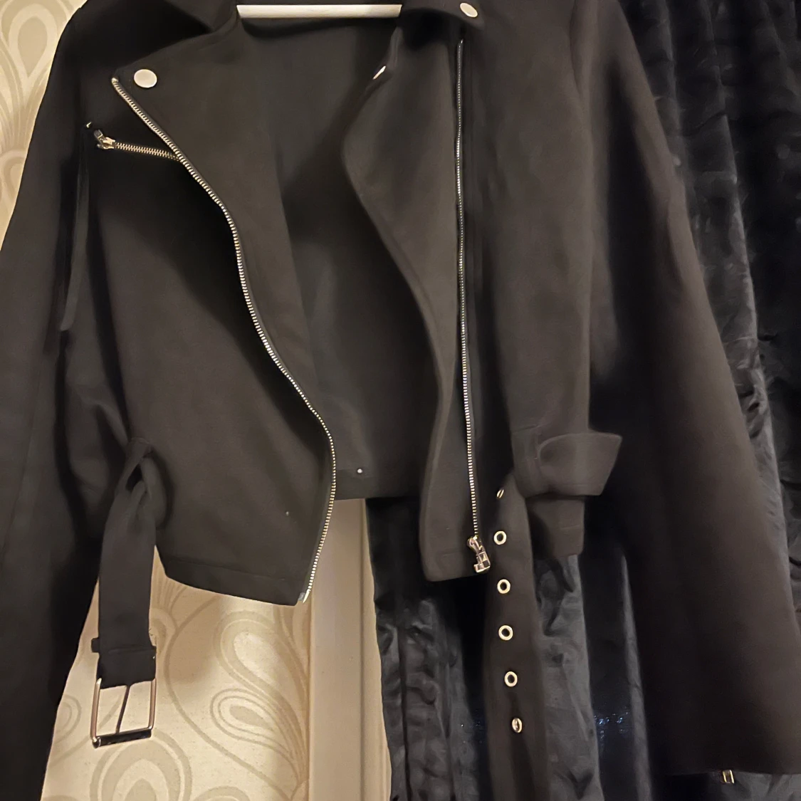 Svart jacka med dragkedja och bälte