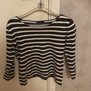 Mörkblåvit randig tröja från Åhléns - Säljer en stilren svartvit randig tröja från Åhléns. Tröjan har trekvartsärmar och en klassisk rund halsringning. Perfekt för en avslappnad look.