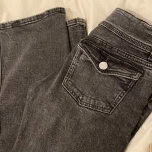 Svarta jeans från Gina Tricot - Snygga svarta jeans från Gina Tricot i storlek 46. De har en klassisk design med två knappar och bälteshällor. Perfekta för en stilren look.