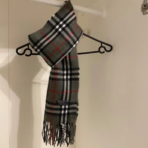 Burberry - Säljer nu denna Snygga halsduk från Burberry i färgen grå. Tillverkad i mjukt lammull med klassiskt fransad kant. Perfekt för att hålla dig varm och stilren under kyliga dagar. Hör av er vid funderingar☺️