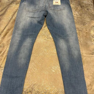 Blå jeans från Dsquared2 - Snygga blå jeans från Dsquared2 med en klassisk femficksdesign och lätt slitna detaljer. De har en dragkedja och knapp framtill. 