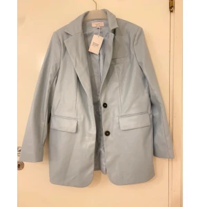 Ljusblå kavaj - Snygg ljusblå kavaj med klassisk design och två knappar framtill. Kavajen har långa ärmar och fickor med lock. Perfekt för en stilren look. Oanvänd kavaj (prislapp fortfarande kvar) i storlek 38, M🩵