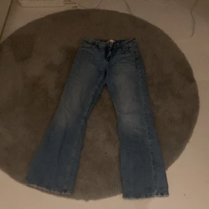 Blå bootcut jeans - Säljer ett par klassiska blå bootcut jeans. De har en snygg utsvängd stil som ger en retro känsla. Perfekta för en avslappnad look.