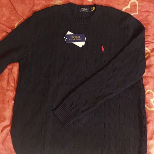 Polo Ralph Lauren Marinblå - Säljer en vacker marinblå stickad tröja från Ralph Lauren med det klassiska röda logotypbroderiet på bröstet. Tröjan har en rund halsringning och är perfekt för kyligare dagar. Det syns inte på bilden att den är marinblå men det är den. Såklart äkta också. Priset kan diskuteras vid snabb affär