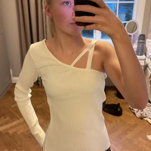 Vit ribbad oneshoulder-topp - Säljer en stilren vit ribbad topp med oneshoulder-design och en extra axelrem. Perfekt för en trendig look. Från Zara storlek L men sitter som en S eller M