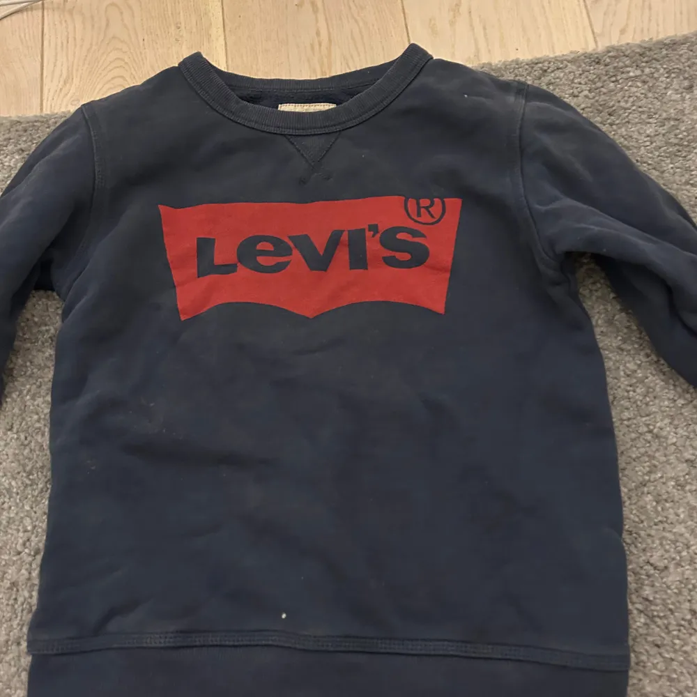 Säljer en mörkblå tröja från Levi's med det klassiska röda logotyptrycket på framsidan. Tröjan har långa ärmar och en rund halsringning. Perfekt för en avslappnad stil. Str 10 år. Neuletakit & Villapaidat.
