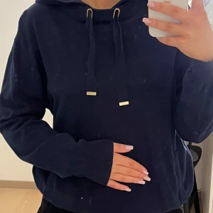 Mörkblå stickad hoodie - Säljer en stilren mörkblå stickad hoodie. Perfekt för en avslappnad look. Super skönt material, vet ej storlek eller märke
