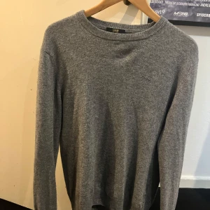 Grå tröja från Cavalli Class - Säljer en stilren grå tröja från Cavalli Class. Tröjan är tillverkad i en mjuk blandning av viskos, polyamid, ull och kashmir, vilket ger en lyxig känsla. Perfekt för kyligare dagar.