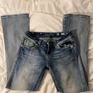 Miss me jeans - Snygga blå miss me jeans med jätte snygga glittriga bakfickor. De har en låg midja och bootcut-stil som ger en avslappnad look. Perfekta för dig som vill ha något unikt i garderoben! Fick dem här jätte snygga miss me jeansen i julklapp men dem var tyvärr lite för stora för mig därför jag säljer. Dem har inga dåliga effekter! Midjemått: 35 cm Innerbenslängd: 78 cm Rise: 19-20 cm passade mig perfekt i längden jag är 167cm lång skriv privat innan du köper eller har några fler frågor!!!💕