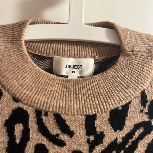 Leopardmönstrad klänning från Object - Snygg leopardmönstrad klänning från Object i brunt och svart leopard mönster. Klänningen har långa ärmar och en rund halsringning. 