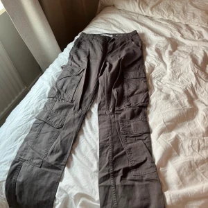 Grå cargobyxor från Bershka - Snygga grå cargobyxor från Bershka med flera praktiska fickor. Perfekta för en avslappnad stil med en loose passform. Tillverkade i ett slitstarkt material som passar bra för vardagsbruk.