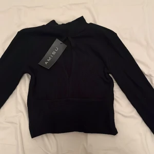 Svart polotröja från Amisu - Snygg svart polotröja från Amisu i mediumstorlek. Tröjan har en ribbad struktur och långa ärmar, perfekt för kyligare dagar. Den har en stilren design som passar till många olika outfits.