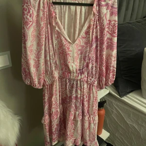 Zara klänning med mönster - Rosa/vit/lila mönstrad klänning från zara. Den har en v-ringad hals och långa ärmar med elastisk midja för en bekväm passform.