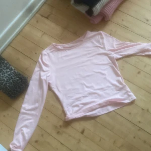 Ljusrosa långärmad topp - Säljer en söt ljusrosa långärmad topp i mjukt material. Perfekt för en avslappnad stil. Toppen har en enkel design utan mönster eller detaljer.