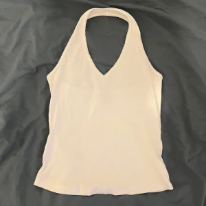 Vit ärmlös topp från Bik Bok - Snygg vit ärmlös topp från Bik Bok med halterneck-design och v-ringning. Perfekt att ha på fest! Enkel och stilren look som passar till det mesta. Aldrig använd så därav mycket bra skick. Storlek M (jag har oftast s/m och den sitter bra på mig). Stretchiga material. Skriv gärna vid frågor🤗