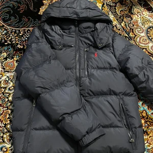 Mörkblå polo jacka - Säljer en snygg mörkblå  från Polo Ralph Lauren med huva och dragkedja. Jackan har en broderad röd logotyp på bröstet och praktiska fickor med dragkedjor. Perfekt för kyliga dagar! Och oanvänd!