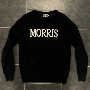 Svart tröja från Morris - Snygg svart tröja från Morris med vit text på bröstet. Tröjan har ribbade muddar och rund halsringning, perfekt för en stilren look. Storlek S, men passar både S och M.
