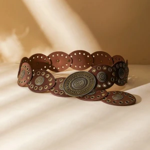 Brunt bälte med metalliska detaljer - Säljer ett unikt brunt bälte med stora runda plattor och detaljer i metall. Bältet har ett bohemiskt och vintage-inspirerat utseende med intrikata mönster på varje platta. Perfekt för att ge en outfit en extra touch av stil och karaktär.