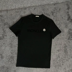 Moncler T-shirt - Säljer nu en riktigt snygg Moncler T-shirt i mycket bra skick! Den är 100% äkta då den är kontrollerad av oss ! Hör av dig vid frågor eller funderingar!