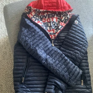 Vändbar tunn täckjacka - Tunn täckjacka herr stl M Vändbar: navy med röd huva ena sidan andra vit med rött o blått tryck ”just over the topp”