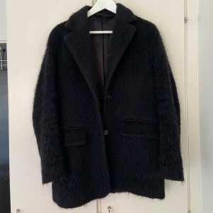 Svart kappa & other stories - Svart mellanlång kappa i en blandning av bland annat ull, alpacka och mohair. Innerficka och två fickor på utsidan. Knappar. Värmer bra på vintern. Fint skick! Storlek XS.