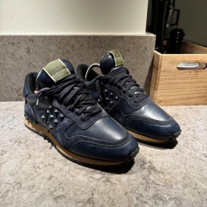 Valentino Garavani Rockrunners  - Ett par snygga mörkblåa rockrunners i ett bra skicka. Har kan du få dom för bara 1499kr då ny pris ligger på 6999kr. Två spikar saknas. Vid mer frågor eller bilder är det bara att skriva. 