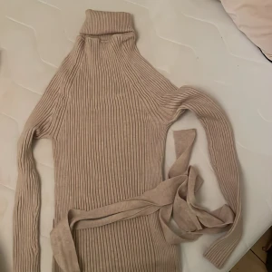 Poloklänning - Jättemjukt och stretchigt material med knytband i midjan. Midilängd med slits längst ner. Nyskick.