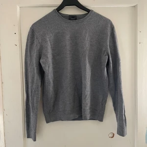 Grå merinoulltröja från H&M - Säljer en stilren och bekväm grå tröja i merinoull från H&M. Perfekt för kyliga dagar med sin mjuka och värmande kvalitet. Tröjan har en klassisk design med långa ärmar och rund hals. Passar både till vardags och lite finare tillfällen. 🐑✨