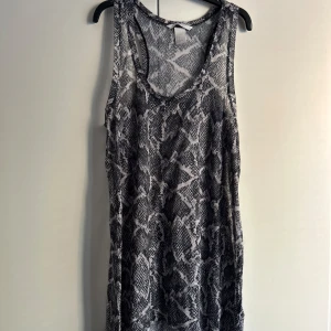  Linnetopp från H&M med ormskinnsmönster - Säljer en snygg ormskinnsmönstrad linnetopp från H&M i storlek S. Den är ärmlös och har en bekväm passform. 