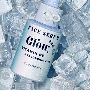 Face Serum Glow - Säljer ett lyxigt ansiktsserum med Vitamin B5 och hyaluronsyra för en strålande hy. Flaskan är ljusblå med en söt pärldetalj i form av en rosett på pipetten. Perfekt för att ge huden extra fukt och lyster. Innehåller 30 ml.