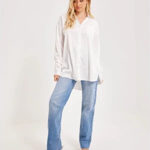 Vit oversized skjorta - Säljer en stilren vit skjorta i oversized passform. Perfekt för en avslappnad look eller att klä upp med accessoarer. Skjortan har långa ärmar och knappar framtill. Den är gjord i ett mjukt och bekvämt material, vilket gör den idealisk för både vardag och fest. Passar perfekt till jeans eller kjol!