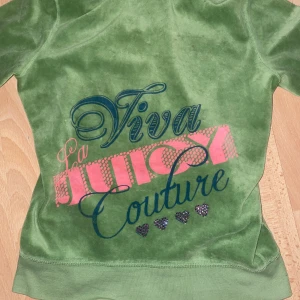 Grön Juicy Couture hoodie - Säljer en supermjuk och snygg grön hoodie från Juicy Couture. Den har en dragkedja framtill och ett stort tryck på ryggen med texten 'Viva La Juicy Couture' i rosa och blått. Sitter bra vid midian så man får den där snatched midian. Säljer för att det inte är min stil längre. 