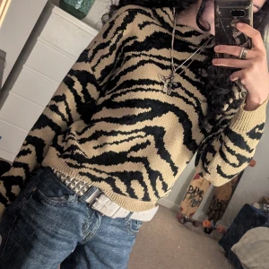 Zebramönstrad stickad tröja - Säljer en supercool zebramönstrad stickad tröja i beige och svart. Den har långa ärmar och en bekväm passform som är perfekt för höst och vinter. 
