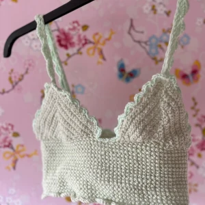 Grön virkad linnetopp - Säljer en superfin grön virkad linnetopp med smala axelband och volangdetaljer. Perfekt för sommardagar eller som ett sött lager under en kofta. Toppen har en skön och luftig passform, idealisk för varma dagar. Passar både till jeans och kjol för en avslappnad look.