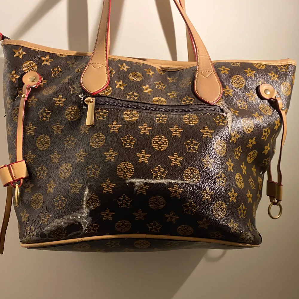 Säljer en snygg brun axelväska från Louis Vuitton med klassiskt monogrammönster i guld. Väskan har ljusbruna handtag och detaljer, samt en praktisk dragkedja på baksidan. Perfekt för både vardag och fest! 👜✨. Väskor.