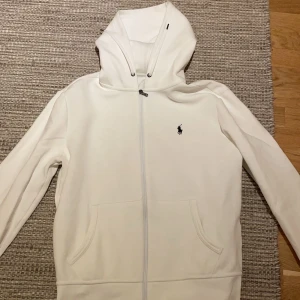 Vit hoodie från Ralph Lauren - VIT RALPH LAUREN HOODIE.                                    Säljer zipen då den är för liten för mig. Hoddiens skicka är 9/10 och är typ som ny.                               Passar dig som är runt 180