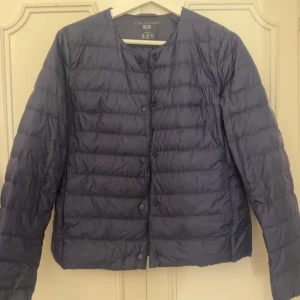 Blå dunjacka från Uniqlo - Säljer en snygg blå dunjacka från Uniqlo i mycket bra skick. Jackan är lätt och perfekt för kyliga dagar. Den har långa ärmar och knappar framtill. Passar perfekt till både vardag och utflykter. 🧥💙Den sitter som en S