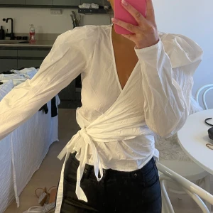 Vit omlottblus - Säljer en superfin vit omlottblus med långa ärmar och knytband i midjan. Som ny😇
