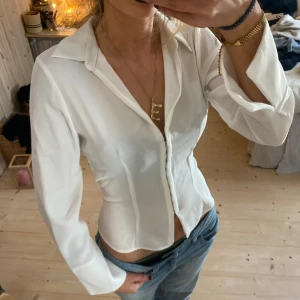 Vit skjorta med knappar - Säljer en stilren vit skjorta med knappar framtill. Skjortan har en tight passform och långa ärmar, perfekt för både vardag och fest. Den är gjord i ett mjukt och bekvämt material som känns skönt mot huden. Passar bra till jeans eller kjol för en chic look❤️❤️❤️