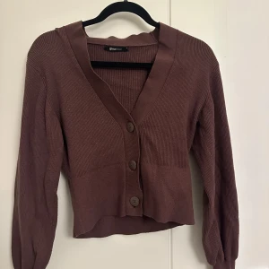Brun ribbad kofta från Gina Tricot - Säljer en snygg brun ribbad kofta från Gina Tricot i storlek S. Den har stora knappar framtill, sitter fint vid midjan och långa ärmar. Perfekt för höst och vår! 🧡