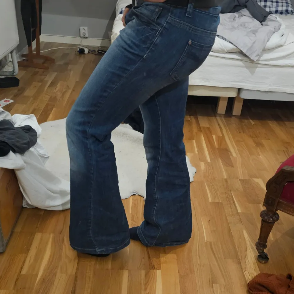 Säljer ett par snygga blå bootcut jeans i bra skick. Jeansen har en bekväm passform och är tillverkade i slitstarkt denim. Midja 42cm ytterbenslängd 107cm jag är 171 som referens. Pris är diskuterbart. Jeans & Byxor.