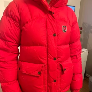 Röd dunjacka från Fjällräven - Säljer min fina röda fjällräven jacka. Så skön och fin. Väl använd men mycket bra kvalite. Rekommenderar starkt❤️ skriv för fler bilder/frågor. Hör av er vid intresse/köp.❤️❤️köp direkt för 4000kr! Jackan behövs tvättas!!!!