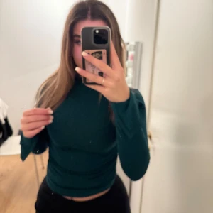 Mörkgrön långärmad topp - Säljer en snygg mörkgrön långärmad topp i mycket bra skick. Den är tight och croppad, perfekt för höst och vår. Toppen är stilren och passar både till vardags och fest. Skicka ett meddelande vid intresse!