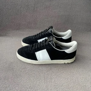 Valentino sneakers i svart och vit mocka - Säljer ett par snygga Valentino sneakers i svart och vit mocka. De har en klassisk design med snörning och en vit sula. Perfekta för både vardag och fest! Skorna är i mycket bra skick och redo för nya äventyr. Storlek 41 passar däremot 42. 3199 kr