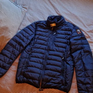 Blå dunjacka  Parajumpers - Säljer en snygg blå dunjacka från Parajumpers i mycket bra skick. Jackan har en quiltad design med dragkedja och en cool patch på ärmen. Perfekt för höst och vinter, håller dig varm och stilren. Passar både till vardags och lite finare tillfällen. 🧥💙